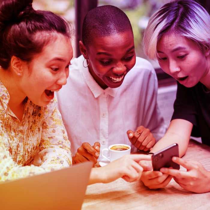 Diversas pessoas entusiasmadas observando o sucesso da empresa nas mídias sociais em um smartphone